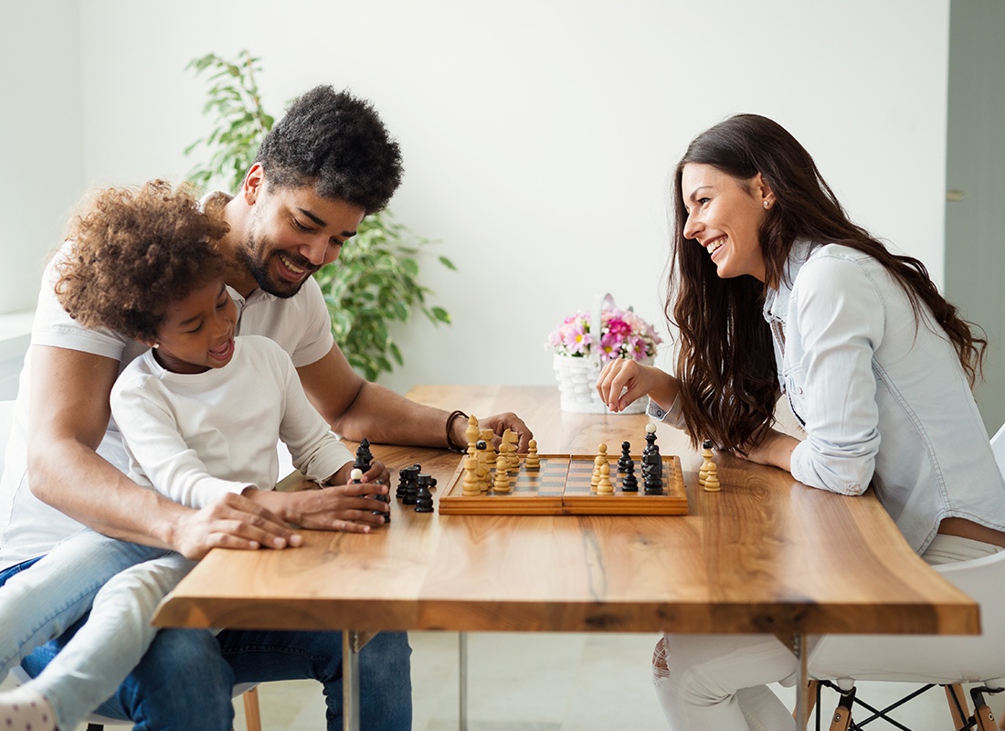 Personal Insurance - Happy Family Sitting Down Together Playing Chess at Home